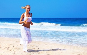 Smiling woman running on beach